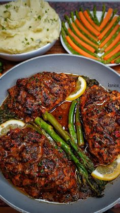 a plate with meat, asparagus and mashed potatoes next to carrots