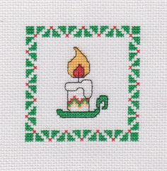 a cross stitch pattern with a candle in the middle and a green frame around it