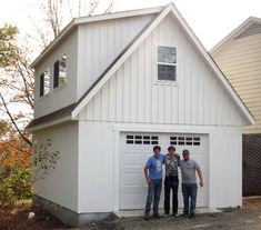 three men standing in front of a white garage with two windows on each side and one door open