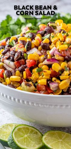 black bean and corn salad in a white bowl with cilantro, lime wedges on the side