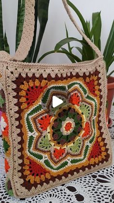 a crocheted bag sitting on top of a table next to a potted plant