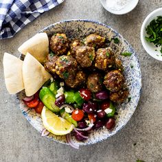 a bowl filled with meatballs, vegetables and pita bread on top of a table