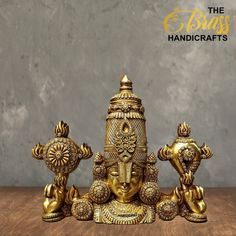 three golden ganeshi statues sitting on top of a wooden table