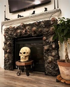 a fireplace with a skull head on the mantle and potted plants next to it