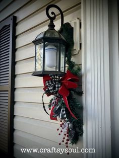 a lantern hanging on the side of a house with a red bow tied around it