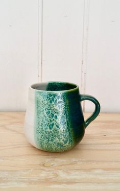 a green and white mug sitting on top of a wooden table