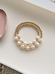 Elevate your style with the Pearl Mommy + Me Bracelet Set. Crafted with luxurious gold beads and pearls, this matching set adds a touch of elegance to any outfit. Perfect for mothers and daughters to showcase their bond, this set is a must-have accessory for any fashionable family. Let us know if you need a custom size! Mommy And Me Beaded Bracelets, Mommy Daughter Bracelets, Elegant Beaded Pearl Bracelet For Mother's Day, Mother's Day Pearl Bracelets, Yellow Gold Pearl Bracelet With Gold Beads For Gift, Gold Pearl Bracelets For Gift, Gold Pearl Bracelet For Gift, Gold Pearl Bracelets As Gift, Mommy And Me Jewelry