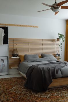 a bedroom with a bed, ceiling fan and pictures on the wall next to it