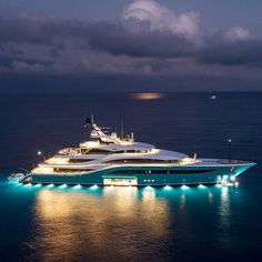 a large blue and white boat in the middle of the ocean at night with lights on it