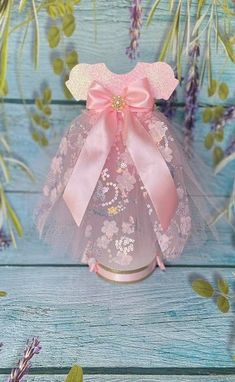 a vase with pink flowers and a bow on it's top sitting on a blue wooden surface