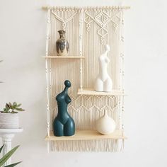 three shelves with vases on them in front of a macrame wall hanging