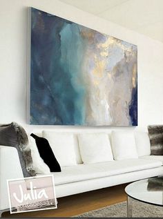 a living room filled with white furniture and a large painting on the wall above it