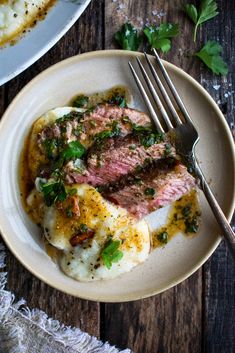 a white plate topped with meat covered in sauce and garnished with parsley