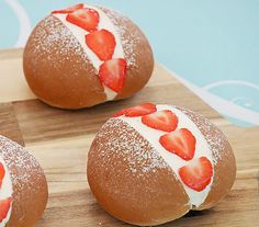 three donuts with strawberries painted on them sitting on a cutting board next to a knife