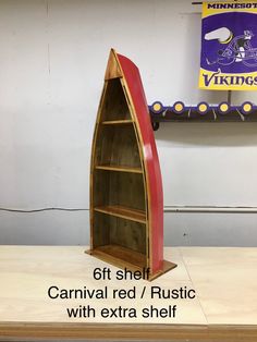 a wooden boat shelf sitting on top of a table next to a sign that says, get shelf carnival red / rustic with extra shelf