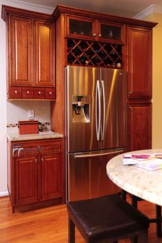 a stainless steel refrigerator in a kitchen with wooden cabinets and marble counter tops, along with a wine rack