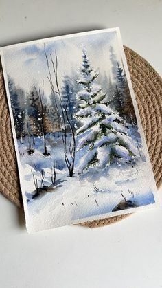 a painting of a snowy pine tree in the woods on a coaster with jute placemats