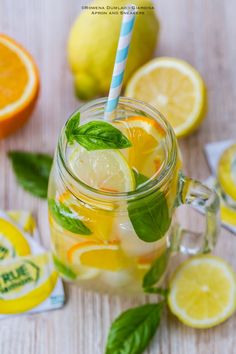 a mason jar filled with lemonade, mint and orange slices on a wooden table