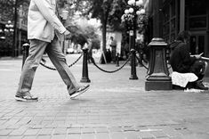 a man is walking down the street with his foot in the air while another person sits on the ground