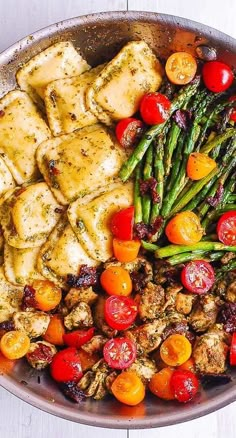 a pan filled with chicken, asparagus and tomatoes