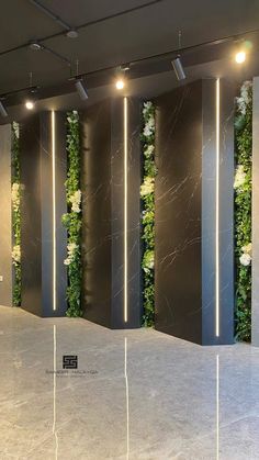 an empty room with some plants growing on the wall and lights hanging from the ceiling