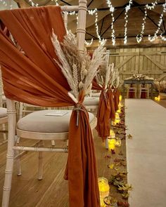 the aisle is decorated with candles and orange drapes for an elegant touch to the ceremony