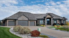 a large house with lots of grass and flowers in front of the entrance to it