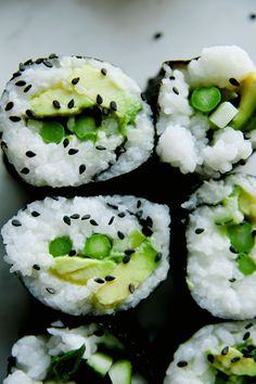 sushi with cucumber, peas and black sesame seeds on it sitting on a white plate