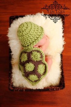 a baby wearing a crocheted turtle hat