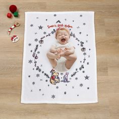 a baby is sitting on the floor with his hands in his mouth and christmas decorations around him