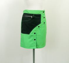 "Original new wrap over rave mini skirt from Toasta in the 1990s.  Made from 100 % polyester in neon green and dark green.  The skirt is straight.   It is silky, matt and of medium weight. Features asymmetric front with 6 press studs, zipped pocket and set in pocket on one side and side pocket with zip on the other.   There were never many of these originally, and probably none now.  Made when trance ruled the world. Size S  UK   10 Flat measurements are;     Waist                   29 inches / 74 cm Hips                     34 inches / 87 cm Back Length        17 inches / 43 cm Weight  121 g For collectables, curios and media visit our sister ETSY shop \" meaningoftime \".  Also check out in this shop, our 2 cutting edge clothing labels JUSTIZ and Corybant, as well as a huge selection of Cyberpunk Outfit Design, Trance Party, Cyberpunk Outfit, Post Apocalyptic Fashion, Kilt Skirt, Tulip Skirt, Apocalyptic Fashion, Clothing Labels, Neon Green