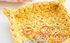 two crocheted baskets with rings on them sitting next to each other, one is yellow and the other is pink