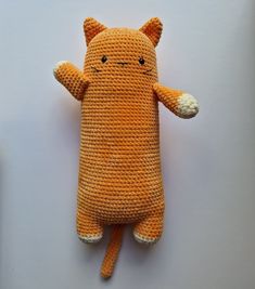 an orange crocheted stuffed animal laying on top of a white table next to a cell phone