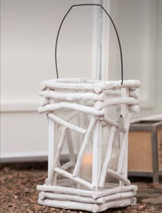 a small white lantern sitting on top of a floor next to a mirror with a lit candle in it