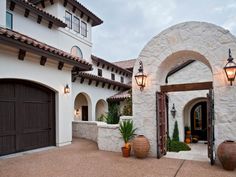 the front entrance to a house with two large brown doors and lights on each side