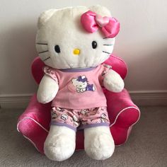 a hello kitty stuffed animal sitting on top of a pink chair next to a wall