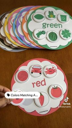 a hand is pointing at some magnets on a table with the words green and red