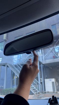 a person is holding their hand up to the side mirror on a vehicle with stairs in the background