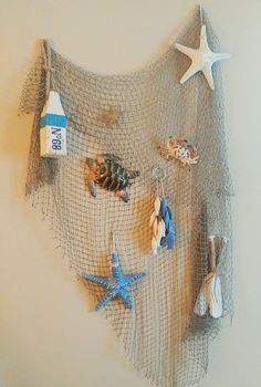 there is a net hanging on the wall with sea shells and starfish