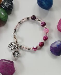 This bangle features a rose shaped locket containing St. Michael and Guardian Angel images. The pink gemstones make up a decade of the Rosary. Valentine's Day Pink Beaded Bracelets With Charms, Pink Beaded Bracelets With Charms For Valentine's Day, Pink Beaded Charms Bracelets For Valentine's Day, Pink Round Beads Jewelry For Mother's Day, Spiritual Pink Personalized Bracelets, Pink Bracelets For Mother's Day, Spiritual Personalized Pink Bracelet, Spiritual Personalized Pink Bracelets, Personalized Pink Spiritual Bracelet