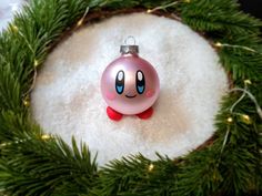 a pink ornament sitting in the middle of a wreath on top of snow