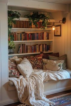 a white couch sitting under a book shelf filled with lots of books next to a window