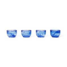 three blue glass cups sitting next to each other on a white surface with water in the middle