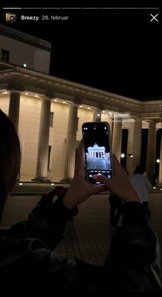 a person taking a photo with their cell phone in front of the white house at night