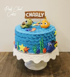 there is a blue cake decorated with fish and an under the sea sign on top