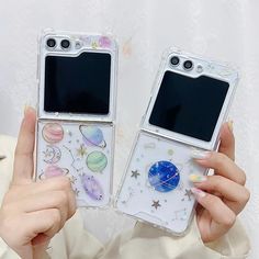 two women holding up cell phones with space stickers on the back and side cases