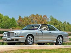 a silver car parked in front of a wooden fence