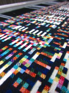 a close up view of a multicolored knitted blanket with squares and lines