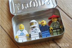 three lego minifigures in a tin on a wooden table with the word'today'written above them