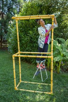 a woman standing on top of a yellow frame in the middle of a grass field